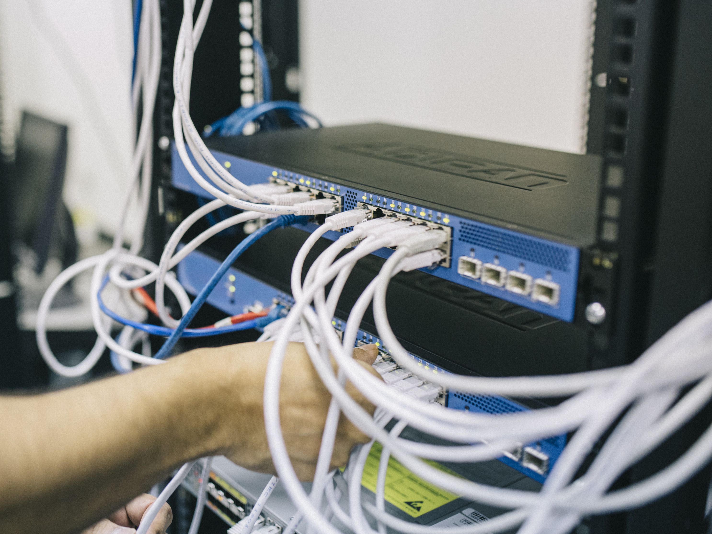 Technician connecting network cables to a rack-mounted switch